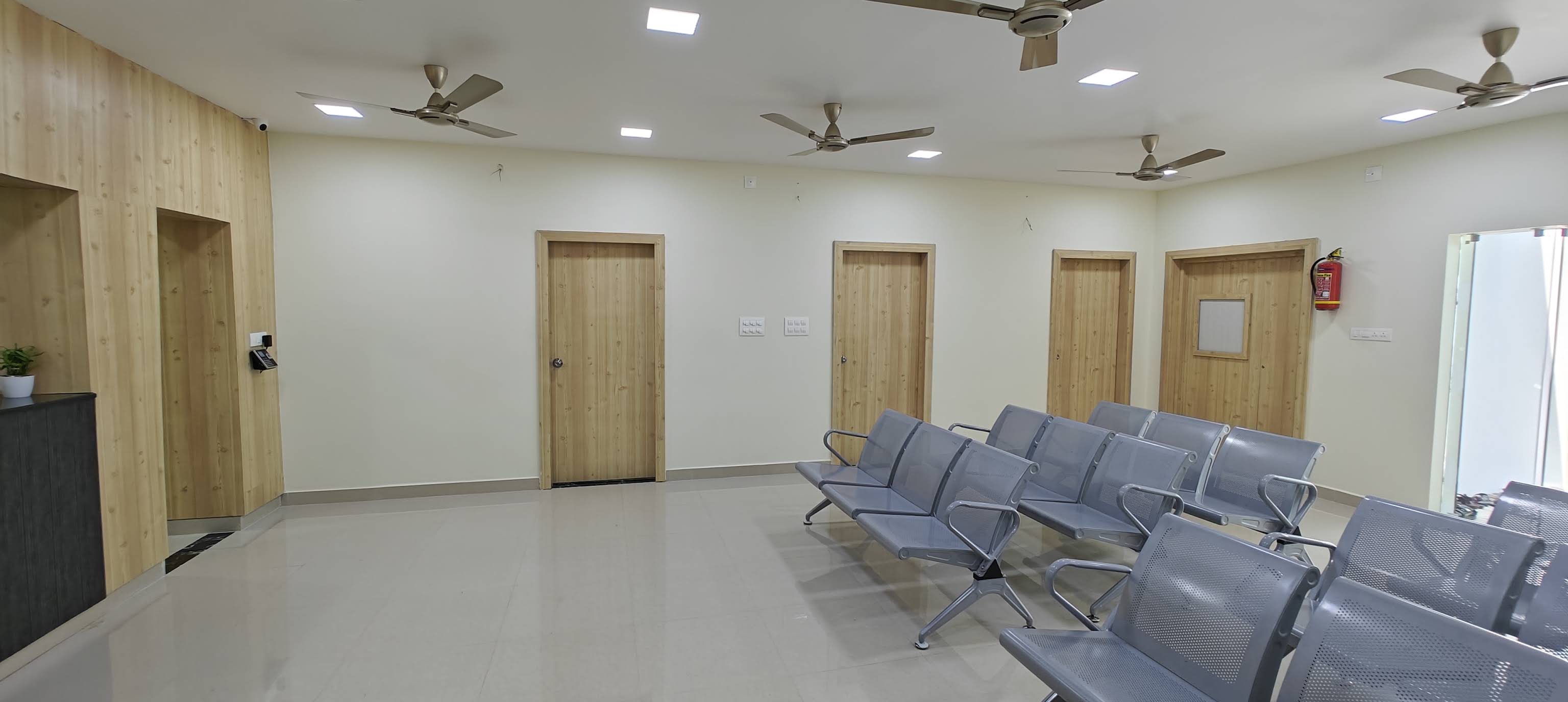 Hospital waiting area with rows of seats and consultation-room doors